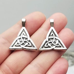 May include: Two silver-toned triangle pendants with a Celtic knot design. The pendants have a loop at the top for attaching to a chain or cord.