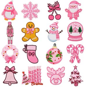 May include: A collection of pink Christmas-themed patches. Designs include a penguin, snowflake, bow, Santa Claus, nutcracker, gingerbread man, snowman, snow globe, wreath, stocking, ornament, candy canes, bell, reindeer, and Christmas tree.
