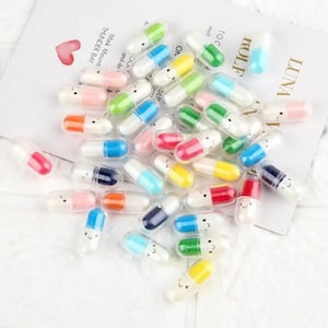 May include: A large pile of colorful plastic capsules with smiley faces on them. The capsules are open and appear to be empty.