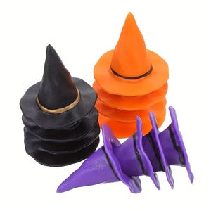 May include: A collection of miniature witch hats in black, orange, and purple. The black hats feature a gold band, the orange hats have a black band, and the purple hats have a black band. These pointed hats are stacked in three separate groups.
