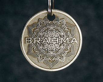 May include: A gold-toned keychain with a mandala design and the word "BRAHMA" inscribed around the center.