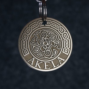 Puede incluir: Llavero de plata con un dise&ntilde;o de nudo celta y la palabra "AKELA" grabada en la parte delantera.