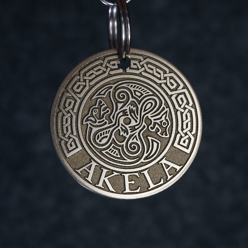 Puede incluir: Llavero de plata con un dise&ntilde;o de nudo celta y la palabra "AKELA" grabada en la parte delantera.