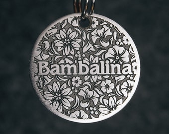 May include: Silver dog tag with a floral design and the name "Bambalina" engraved on it.