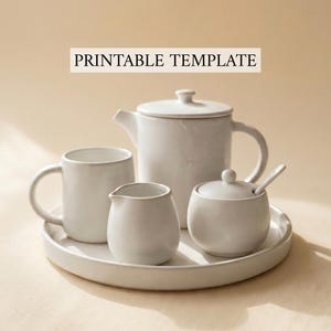 May include: A white ceramic tea set, including a teapot, mug, creamer, and sugar bowl with a spoon, arranged on a round tray. The text "PRINTABLE TEMPLATE" is displayed above the tea set.