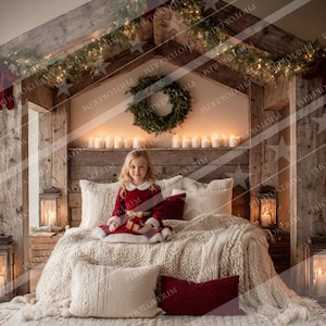 May include: A cozy Christmas-themed bedroom scene. A young person in a red dress sits on a bed with a cream-colored knitted blanket and pillows. The bed is framed by a wooden structure adorned with greenery, lights, and candles. Lanterns and a small Christmas tree add to the festive atmosphere.