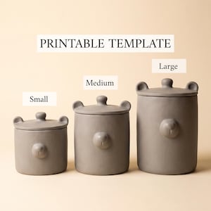 Può includere: Tre contenitori cilindrici grigi con coperchio, ognuno caratterizzato da naso e orecchie da orso. I contenitori sono etichettati come Small, Medium e Large. Il testo PRINTABLE TEMPLATE è visualizzato sopra i contenitori, disposti in fila.