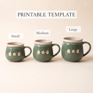 May include: Three green ceramic mugs labeled Small, Medium, and Large, featuring a printable template. Each mug has a light-colored rim and small embossed icons of a house, a star, and a mitten on the front. The text PRINTABLE TEMPLATE is visible.