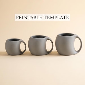 Puede incluir: Tres tazas de cerámica grises de diferentes tamaños, cada una con un cuerpo redondeado y un solo asa. Las tazas tienen un interior gris oscuro y están dispuestas en fila. El texto "PRINTABLE TEMPLATE" se muestra encima de las tazas.