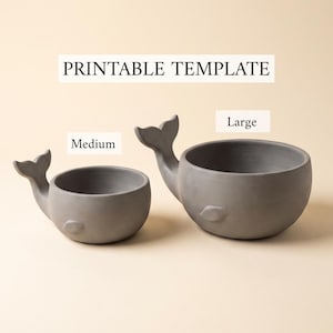 Puede incluir: Dos cuencos grises con forma de ballena, etiquetados como Medium y Large, con un encabezado que dice PRINTABLE TEMPLATE. Los cuencos presentan un cuerpo redondeado, una aleta caudal lateral y una pequeña aleta lateral en la parte frontal.