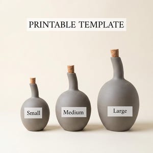 Può includere: Tre bottiglie in ceramica grigia con tappi di sughero in dimensioni piccola, media e grande. Il testo PRINTABLE TEMPLATE appare in alto, con le etichette Small, Medium e Large su ogni bottiglia. Le bottiglie hanno base rotonda e collo stretto.