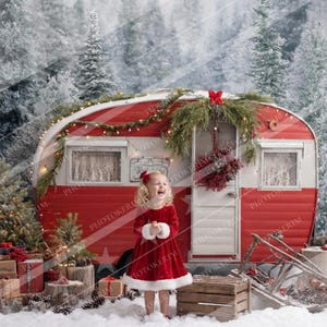 以下が含まれることがあります： 赤と白のキャンピングカーが特徴のクリスマスのシーン。赤いドレスを着た若い人がキャンピングカーの前に立って笑顔を見せています。雪の降る森の中で、クリスマスの飾り付けがされています。