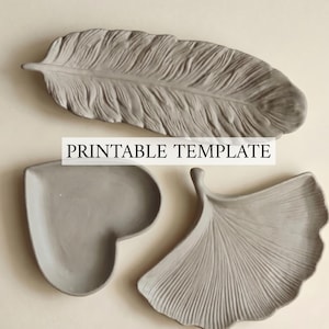 May include: Three gray decorative trays featuring a feather shape, a heart shape, and a ginkgo leaf shape. The text PRINTABLE TEMPLATE is centered across the items. Each tray has a textured surface with detailed ridges and smooth edges.