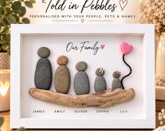 May include: A white framed wall art piece featuring five pebble figures standing on a piece of driftwood. The figures are labelled James, Emily, Oliver, Sophie, and Lily. A pink heart balloon is attached to the smallest figure. Text reads: YOUR FAMILY, Told in Pebbles, PERSONALISED WITH YOUR PEOPLE, PETS & NAMES, Our Family.
