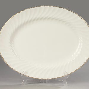 Op de afbeelding: Witte ovale serveerschaal met een gouden rand en een swirl-ontwerp.