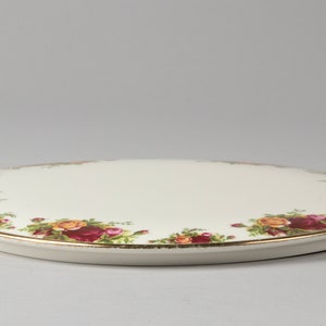 Puede incluir: Plato para pastel ovalado de cerámica blanca con borde dorado y diseño floral con rosas rojas, amarillas y verdes.