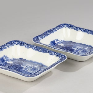 May include: Two blue and white porcelain serving dishes with a decorative border and a blue and white landscape scene.