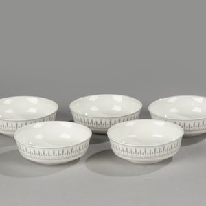 Può includere: Cinque ciotole in ceramica bianca con un motivo geometrico blu e arancione intorno al bordo.