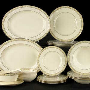 Op de afbeelding: Een set wit porselein serviesgoed met gouden rand. De set bevat borden, kommen en een sauskom.