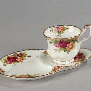 Può includere: Un set da tè in porcellana bianca con un motivo floreale con rose rosse, gialle e rosa. Il piattino ha una forma unica con una sezione rialzata per la tazza.