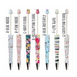 May include: Seven different patterned pens with silver caps and tips. The pens feature designs such as a nurse's uniform, floral patterns, butterflies, and stripes. The pens are labeled with letters A through G.