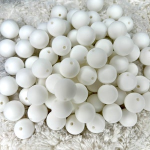 May include: A large pile of white silicone beads. The beads are round and have a hole in the center. They are perfect for making jewelry or other crafts.