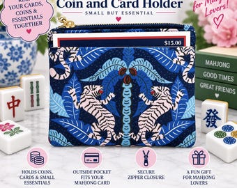 May include: A rectangular coin and card holder featuring a dark blue fabric with a repeating pattern of white tigers and blue palm leaves. The pouch has a gold-toned zipper closure at the top and an exterior pocket containing a card with $15.00 printed.