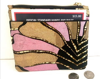 May include: A patterned wallet with a gold zipper, featuring pink, brown, and black floral designs. The wallet has a pocket with a card that reads "OFFICIAL STANDARD HANDS AND RULES" and a price tag of $15.00. Three coins are visible.