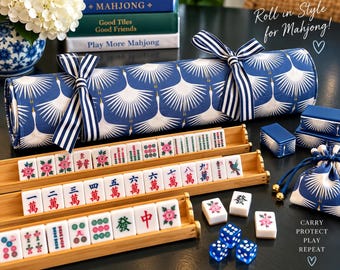 May include: A mahjong set featuring a blue fabric roll with a white crane pattern tied with striped ribbons, three bamboo tile racks, white tiles with colorful symbols and characters, blue dice, and a matching drawstring storage pouch.