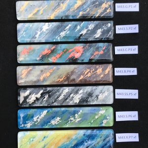 May include: Seven rectangular glass tiles with different abstract designs in shades of blue, green, gold, silver, and copper. Each tile has a label with the text "M43.G.P1 xf", "M43.S.P2 xf", "M43.C.P3 xf", "M43.B.P4 xf", "M43.SS.P5 xf", "M43.S.P6 xf", and "M43.X.P7 xf".