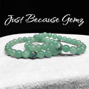 Puede incluir: Tres pulseras de cuentas de jade verde apiladas sobre una superficie blanca. Las pulseras están hechas de cuentas redondas y tienen aproximadamente 18 cm de largo.