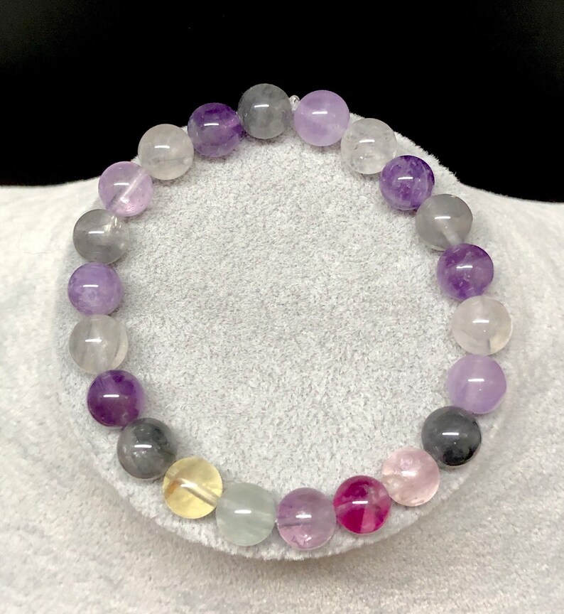 Puede incluir: Una pulsera de cuentas con una variedad de piedras preciosas coloridas. La pulsera incluye cuentas redondas en tonos de morado, gris, rosa, amarillo y transparente. Las cuentas est&aacute;n ensartadas en un cord&oacute;n el&aacute;stico transparente, creando un accesorio vibrante y llamativo.