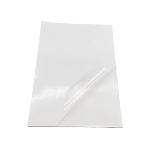May include: A white sheet of adhesive-backed paper with a clear protective layer partially peeled back.