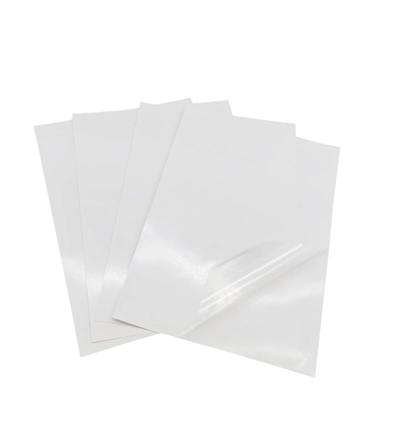 May include: A stack of four white sheets of adhesive-backed paper, with a clear protective layer on top.