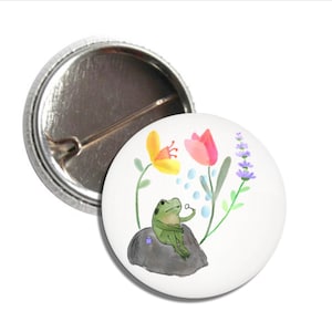 May include: A watercolor illustration of a green frog blowing bubbles on a rock surrounded by flowers. The flowers are yellow, pink, and purple.