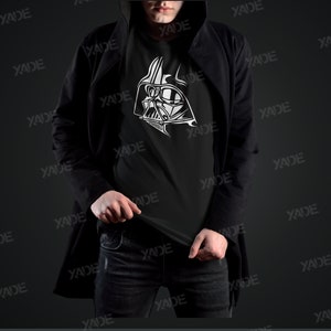 May include: A black t-shirt with a white graphic of Darth Vader's helmet. The person wearing the shirt is wearing a black jacket and blue jeans.