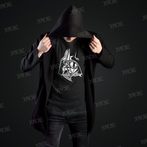 May include: A black hooded jacket with a black t-shirt underneath. The t-shirt has a white graphic of Darth Vader's face on it.