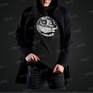 K&ouml;nnte beinhalten: Ein schwarzes T-Shirt mit einem wei&szlig;en Grafikdruck des Todessterns aus Star Wars.