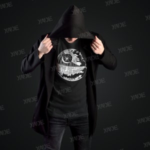 K&ouml;nnte beinhalten: Eine schwarze Kapuzenjacke mit einem schwarzen T-Shirt darunter. Das T-Shirt zeigt ein wei&szlig;es Motiv des Todessterns aus Star Wars.