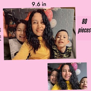 May include: A 80-piece jigsaw puzzle featuring a family portrait. The puzzle shows three people, two children and an adult, smiling at the camera. The puzzle is 9.6 inches wide and 7.7 inches tall.