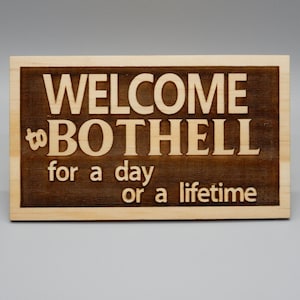 May include: A wooden sign with the text "WELCOME to BOTHELL for a day or a lifetime" in white lettering on a dark brown background.