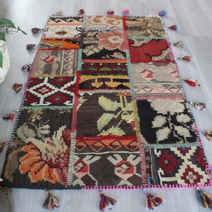 Puede incluir: Una alfombra de patchwork colorida con flecos. La alfombra está hecha de diferentes telas y patrones, incluyendo diseños florales, geométricos y abstractos. La alfombra es una mezcla vibrante de rojo, naranja, amarillo, verde, azul y marrón.