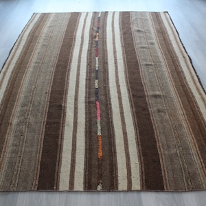May include: A brown and cream striped rug with a colorful woven design down the center.
