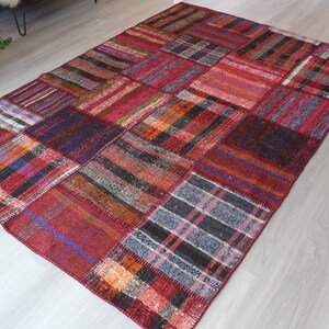 K&ouml;nnte beinhalten: Ein roter, blauer und schwarzer Patchwork-Teppich mit verschiedenen Mustern. Der Teppich ist aus gewebtem Stoff und hat einen Used-Look.