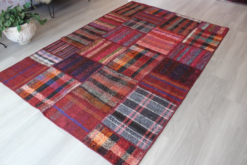 K&ouml;nnte beinhalten: Ein roter, blauer und schwarzer Patchwork-Teppich mit verschiedenen Mustern. Der Teppich ist aus gewebtem Stoff und hat einen Used-Look.