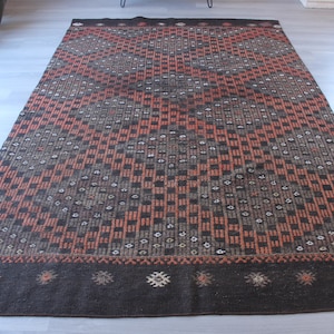 May include: A black and orange patterned rug with a geometric design. The rug has a black border with a small, intricate pattern.