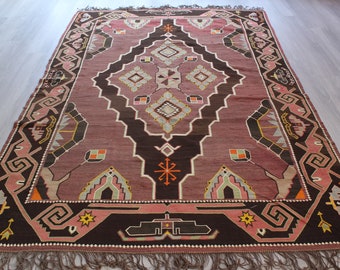 May include: A vintage rug with a geometric pattern in shades of pink, brown, and white. The rug has a fringe border and is made of wool.