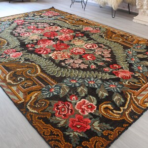 May include: A vintage floral rug with a dark brown background and intricate patterns in shades of red, green, and gold.