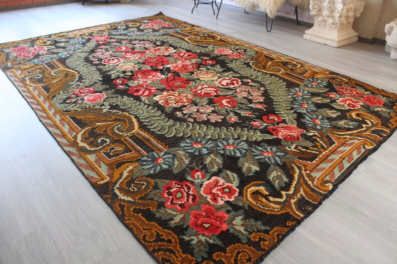 May include: A vintage floral rug with a dark brown background and intricate patterns in shades of red, green, and gold.