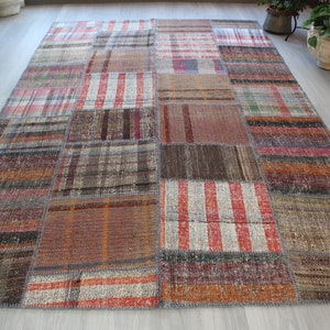 May include: A patchwork rug featuring a mix of colours and patterns, including red, brown, and white. The rug is woven and has a distressed appearance.